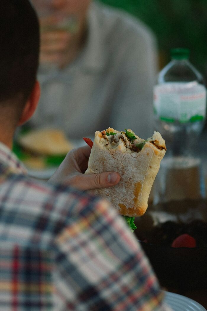 Person holding a half-eaten sandwich on a first date, illustrating disastrous first dates that might make you rethink dating.