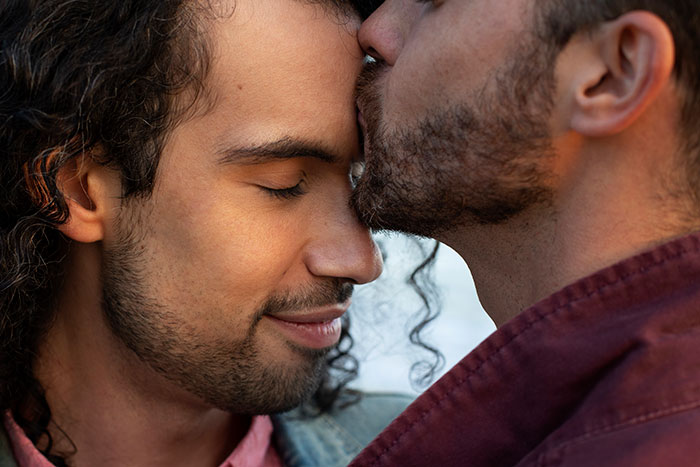 Close-up of a man tenderly kissing his partner&rsquo;s forehead, capturing a heartfelt love story and romantic connection.