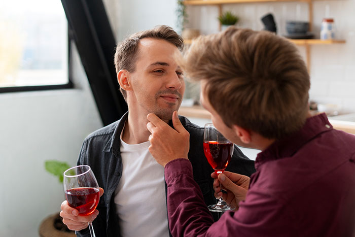 Two men reconnecting over wine, sharing an intimate moment in a cozy home setting highlighting a heartfelt love story.