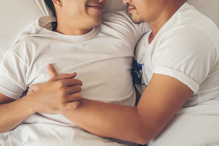 Two men lying close together, sharing a tender moment that captures love story and reconnecting emotions.