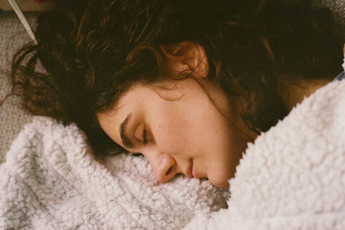 Young woman resting peacefully on a soft textured blanket, reflecting on truths vanished from home countries.