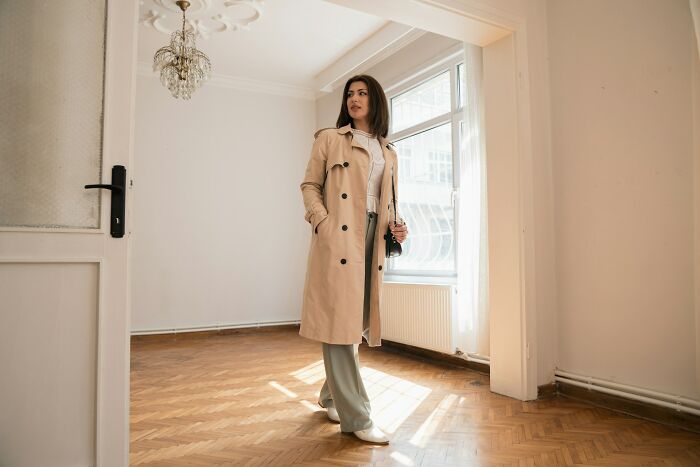 Woman experiencing culture shock standing in an empty room with natural light highlighting wooden floors and white walls.