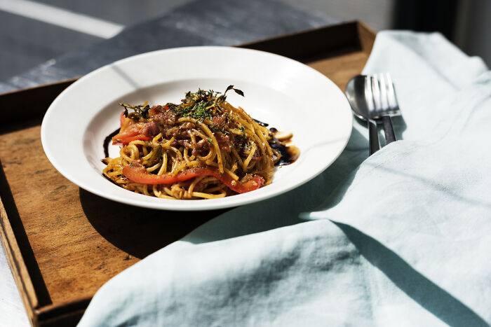 A plate of spaghetti with sauce served on a wooden tray, illustrating customers’ ridiculous complaints in restaurants.