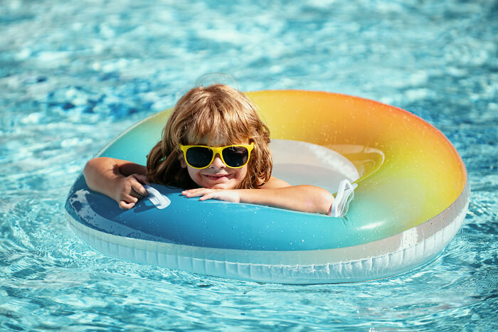 Child wearing yellow sunglasses relaxing in a colorful pool float, illustrating customers’ ridiculous complaints humor.