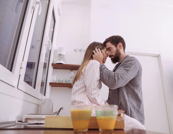 A couple sharing an intimate moment in a kitchen, reflecting on sobering stories of personal hell and ruined lives.