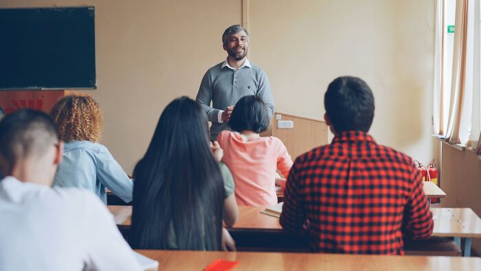 Teacher standing and speaking to a classroom of students, illustrating stories of ruined lives as a life lesson.