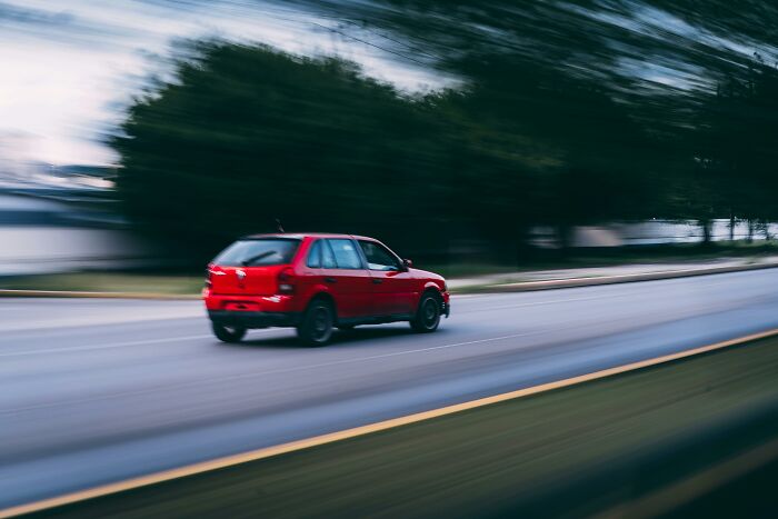 Red car speeding on a blurry road, illustrating a quick shortcut to personal hell and the consequences of ruined lives.