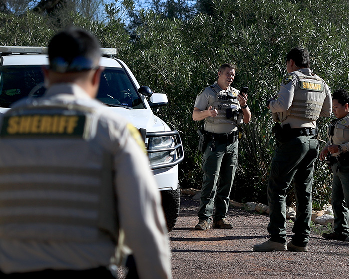 Law enforcement officers in sheriff uniforms discussing FBI analysis related to Nancy Guthrie case theories and new lead.