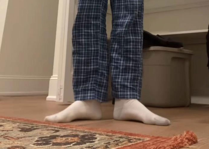 Person standing barefoot in plaid pajama pants on hardwood floor near a rug, symbolizing first dates horrible moments.