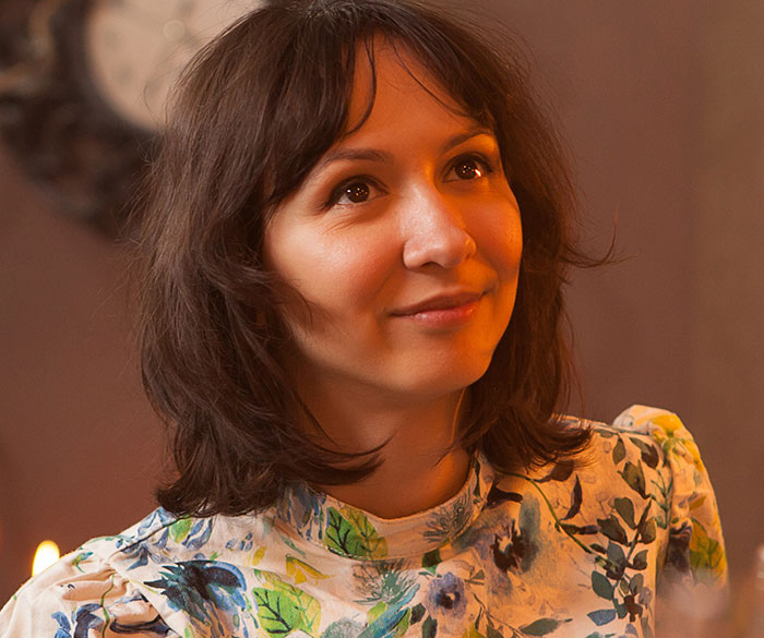 Young woman with floral top smiling thoughtfully, representing first dates and character-building trauma experiences.