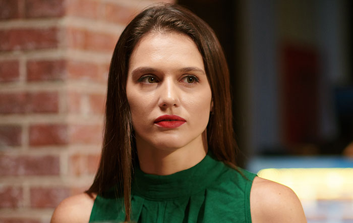 Young woman in a green top with a concerned expression, representing first dates so horrible they cause character-building trauma