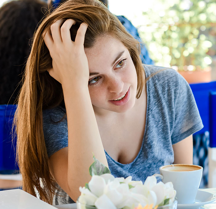 Young woman experiencing awkward emotions on a first date in a cafe, highlighting first dates character-building trauma moments.
