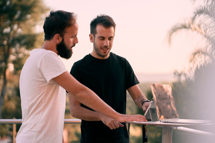 Two men discussing ideas while using a laptop outdoors, reflecting change in ex incels' perspectives.
