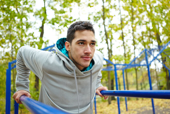 Young man in a gray hoodie exercising outdoors, representing change and growth in the journey of ex incels.
