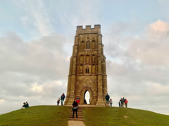 Visitors exploring a famous historic landmark on a hill under a cloudy sky, highlighting popular myths about iconic landmarks.