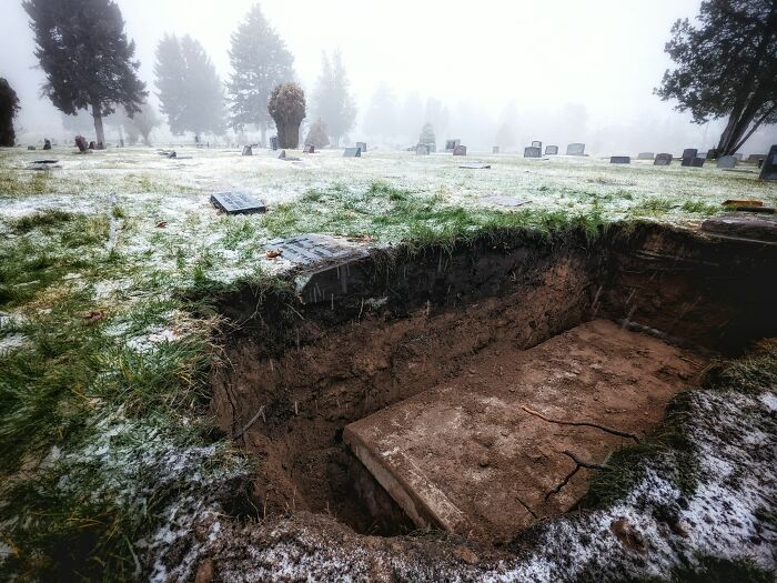 Open grave in a foggy cemetery with frost-covered grass, illustrating wild things funeral directors saw and remember.