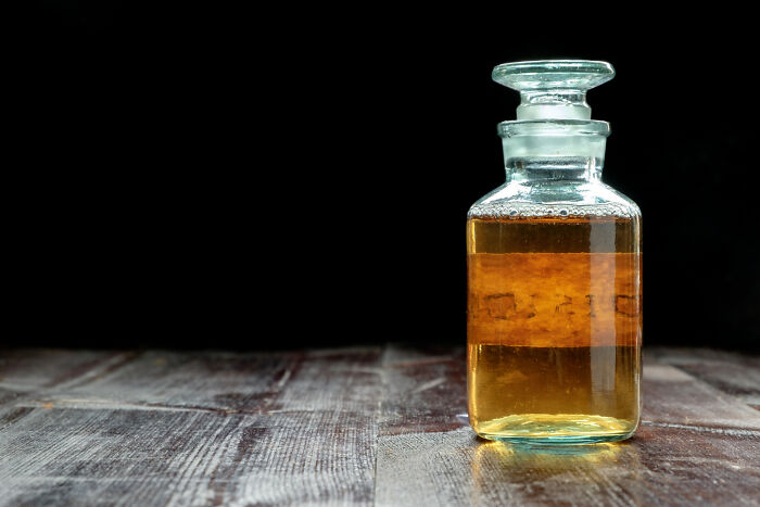 Glass bottle filled with amber liquid on wooden surface, symbolizing unique items funeral directors have encountered.