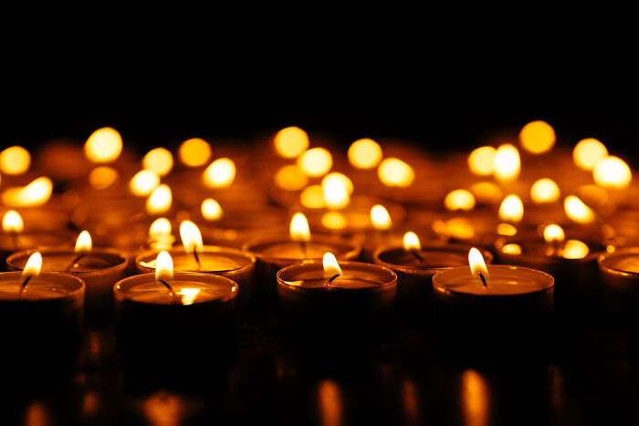 Multiple lit candles glowing softly in a dark room, evoking a serene atmosphere for funeral directors to remember.