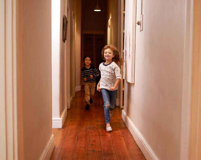Two children running joyfully down a wooden hallway, capturing wild moments funeral directors still remember.