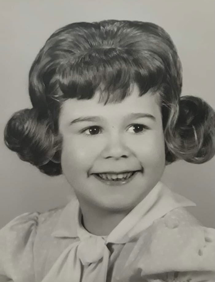 Smiling child with a vintage hairstyle featuring voluminous curls, showcasing a classic hair disaster from childhood photos.