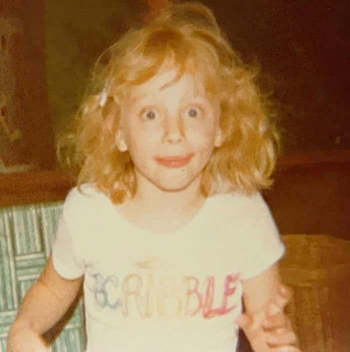 Child with wild curly hair posing indoors, showcasing a classic childhood hair disaster moment.