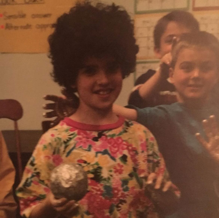Childhood photo of a child with a hair disaster wearing a colorful floral shirt and holding a silver ball.