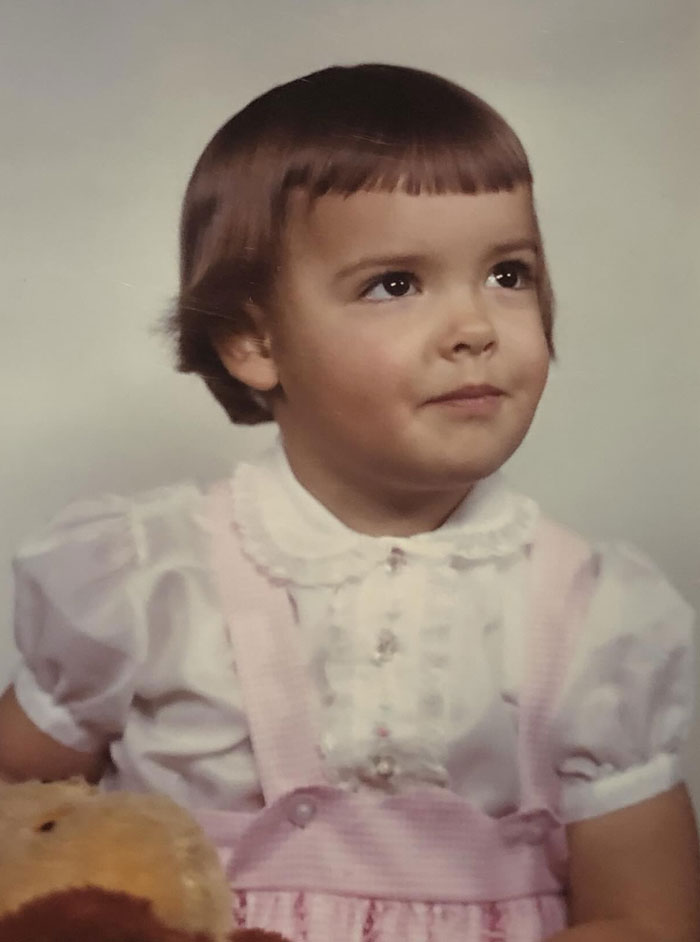 Young child with a vintage hairstyle wearing a pink dress, showcasing a memorable childhood hair disaster moment.