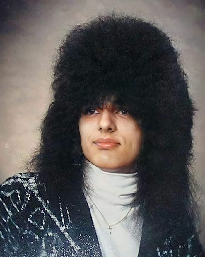 Person posing for a funny school picture day with an exaggerated, voluminous hairstyle and retro clothing style.