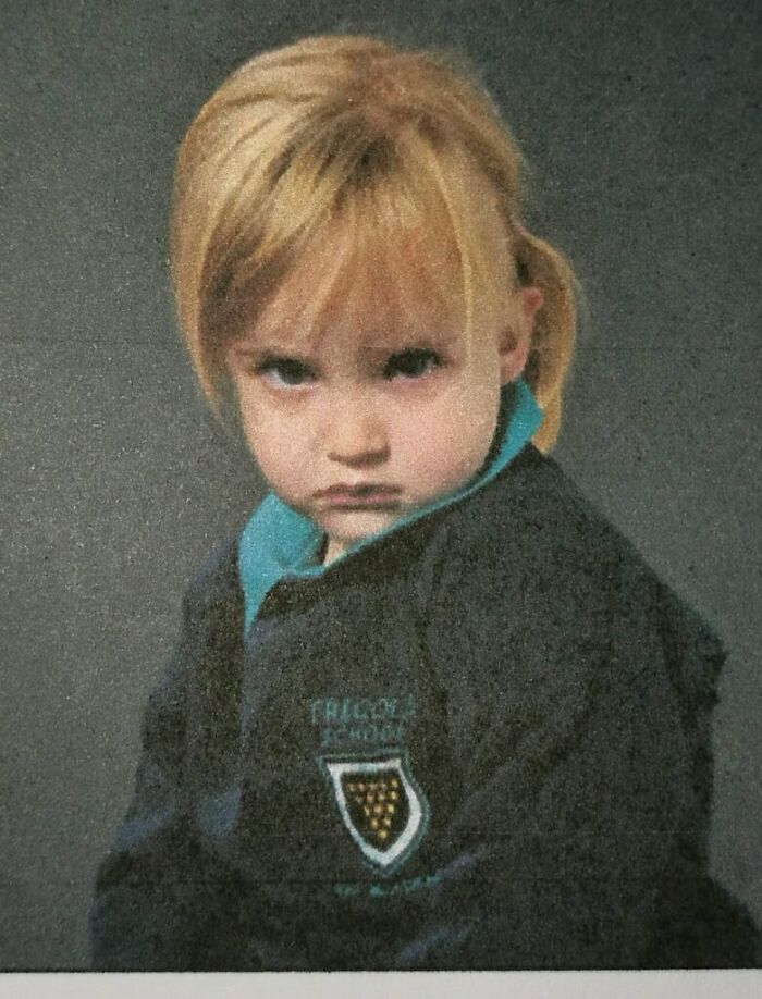 Young girl in school uniform making a funny face during a school picture day fail with a grumpy expression.