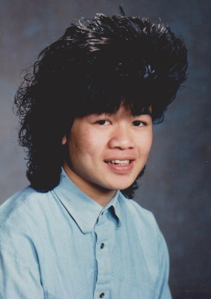 Teen boy with a large vintage hairstyle wearing a light blue shirt posing for funny school picture day fails photo.