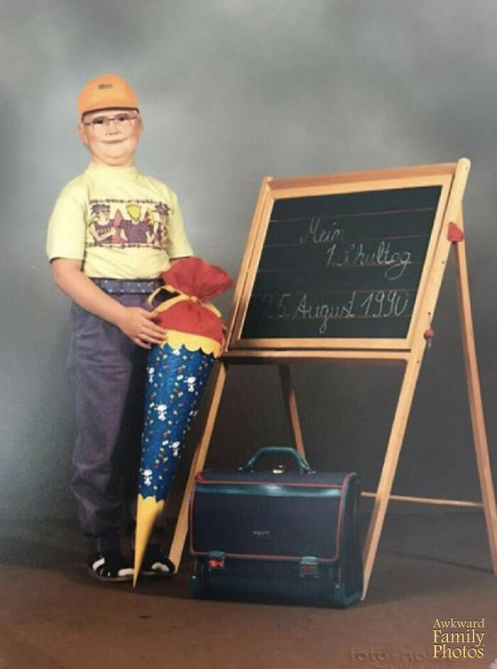 Young boy posing awkwardly on school picture day with oversized cone and chalkboard, a classic funny school picture day fail.