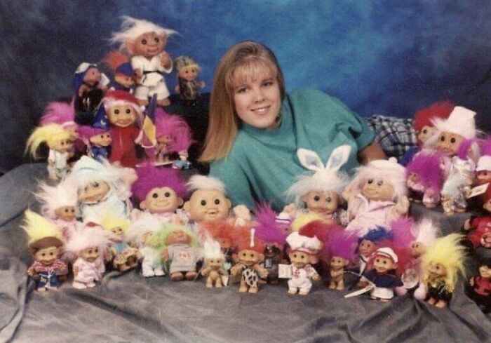 Teen girl posing with colorful troll dolls in a vintage school picture day setting, capturing a funny school picture day fail.