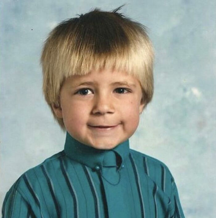 Young boy in a vintage striped shirt posing awkwardly for a funny school picture day fails photo with a rare smile.