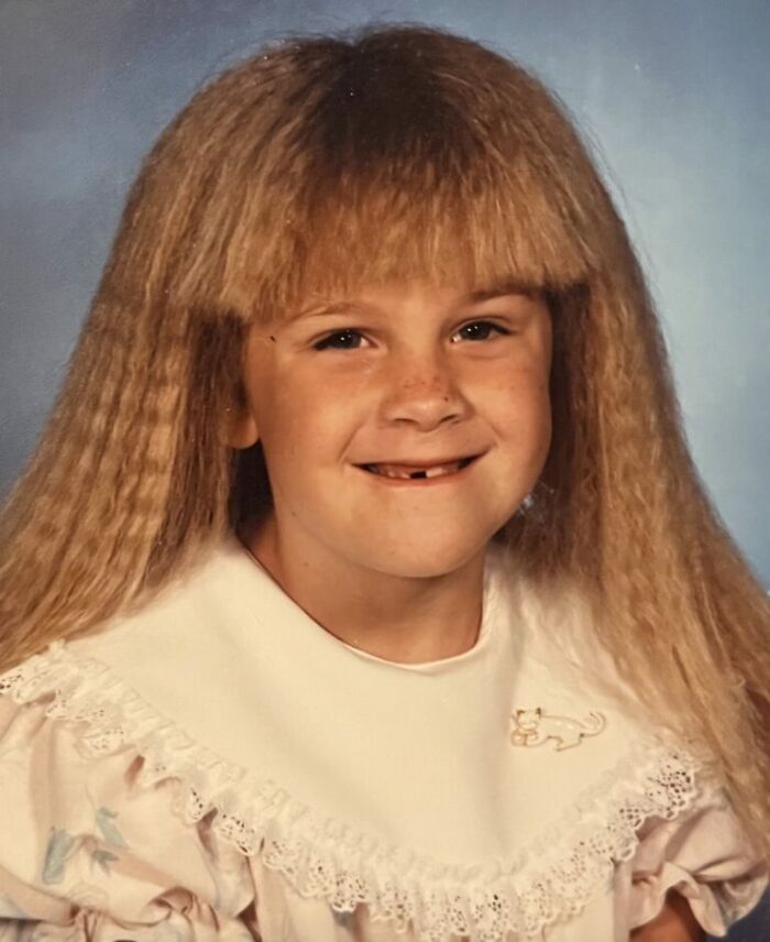 Young girl with crimped hair and missing front teeth in a classic funny school picture day fail portrait.