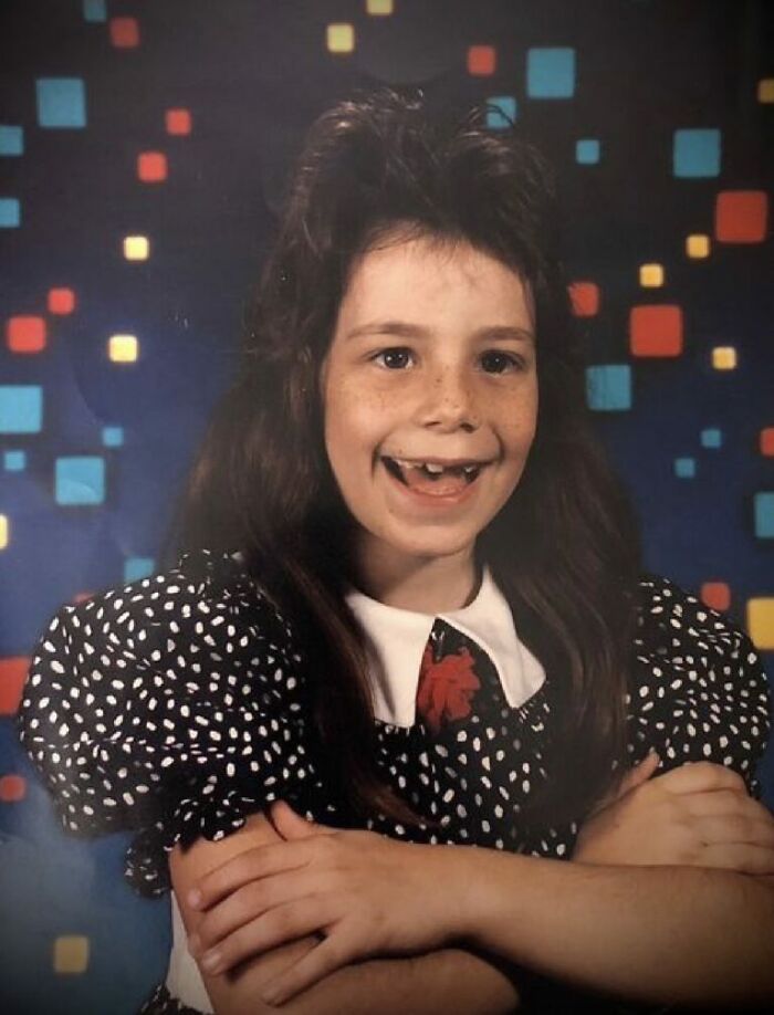 Young girl with messy hair and missing teeth smiling awkwardly in a funny school picture day fail with retro background.