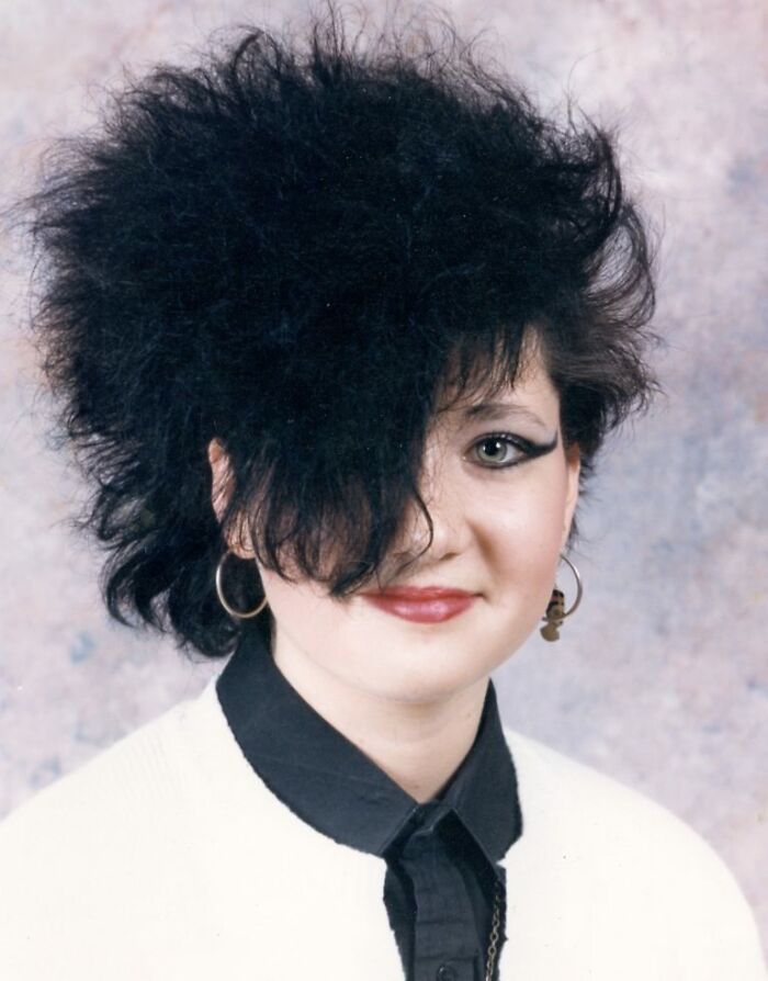 Teen girl with exaggerated teased hair and bold makeup posing for a funny school picture day fail portrait.