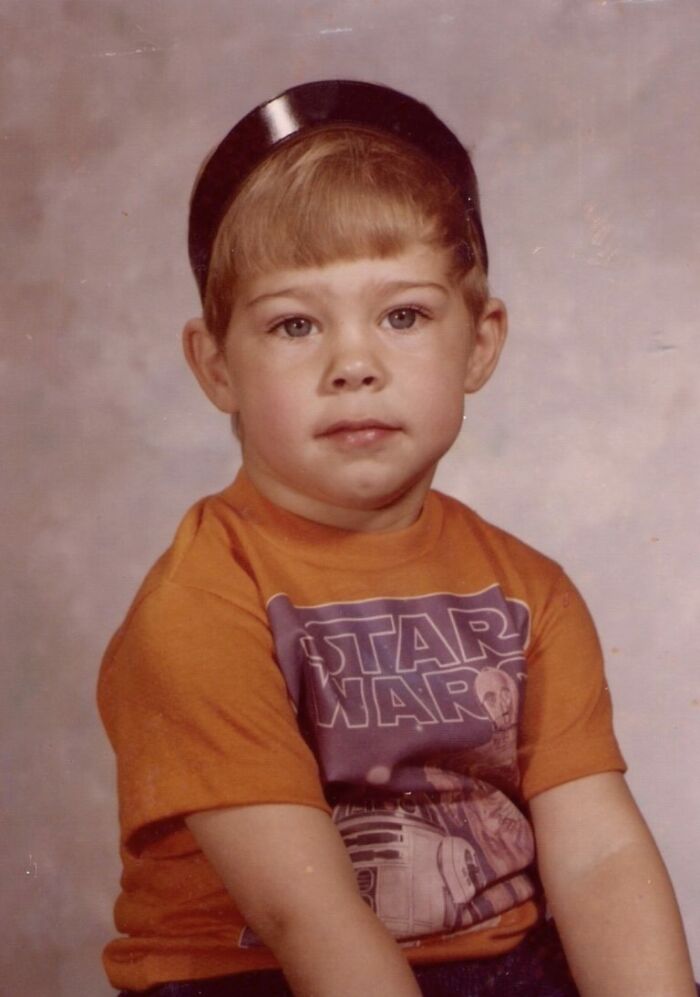 Young boy wearing a Star Wars shirt with a confused expression and a black bowl on his head in a funny school picture day fail.