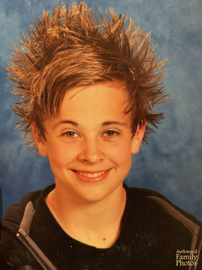 Smiling boy with spiky hair in a classic funny school picture day fail against a blue background.