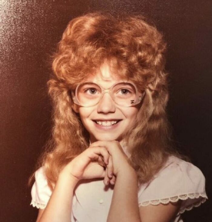Girl with large glasses and big curly hair smiling in a classic funny school picture day fail portrait
