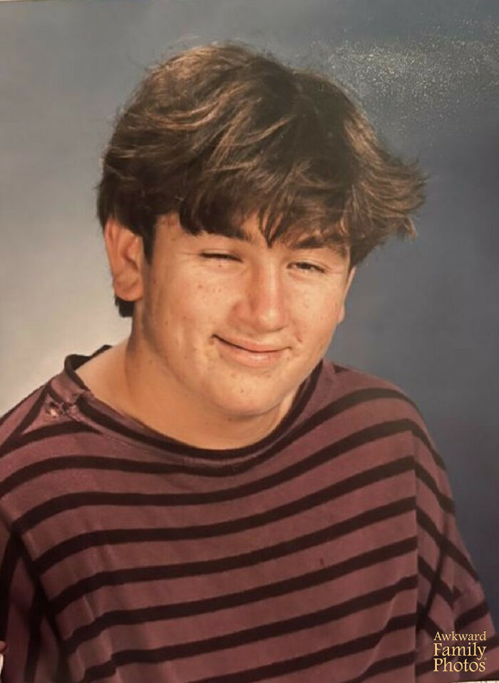 Teen boy in a striped shirt winking during a funny school picture day fail with disheveled hair and a smirk.