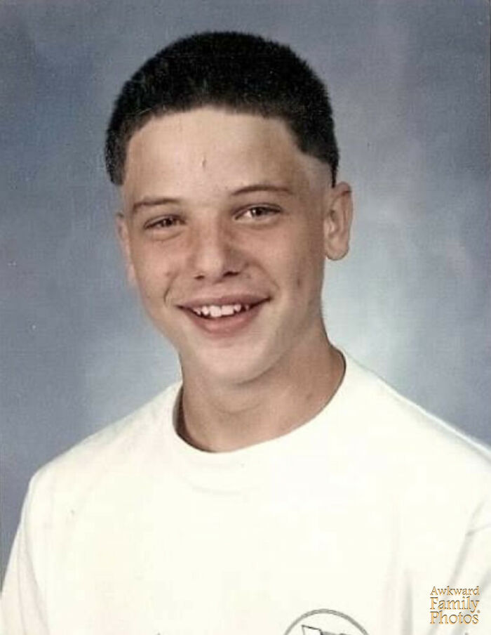 Smiling teenage boy with uneven teeth in a white shirt posing for a funny school picture day fail portrait.