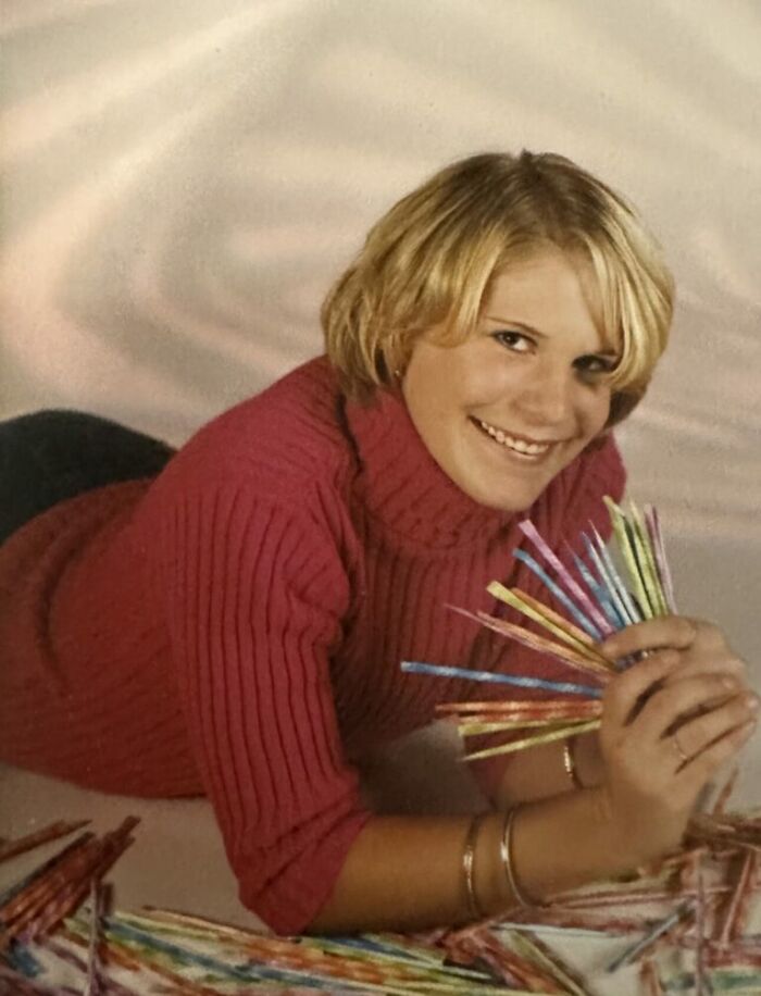 Teen girl in a red sweater posing with colorful straws in a humorous school picture day fail photo session.