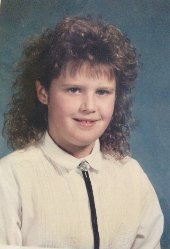 Girl with curly hair and missing teeth posing for a funny school picture day fail with vintage style clothing and background