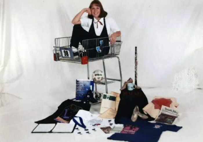 Teen girl posing humorously in a shopping cart surrounded by school supplies in a funny school picture day fail setup.