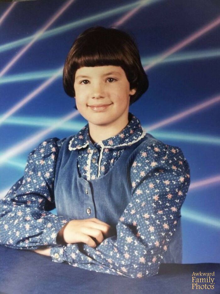 Child with a vintage hairstyle and floral dress posing for a funny school picture day fail with laser background.