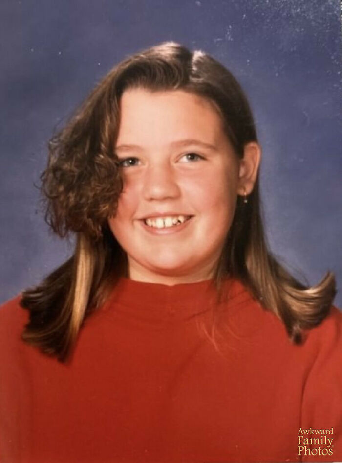 School picture day fail showing girl with uneven hairstyle and missing teeth smiling in a red shirt against a blue background