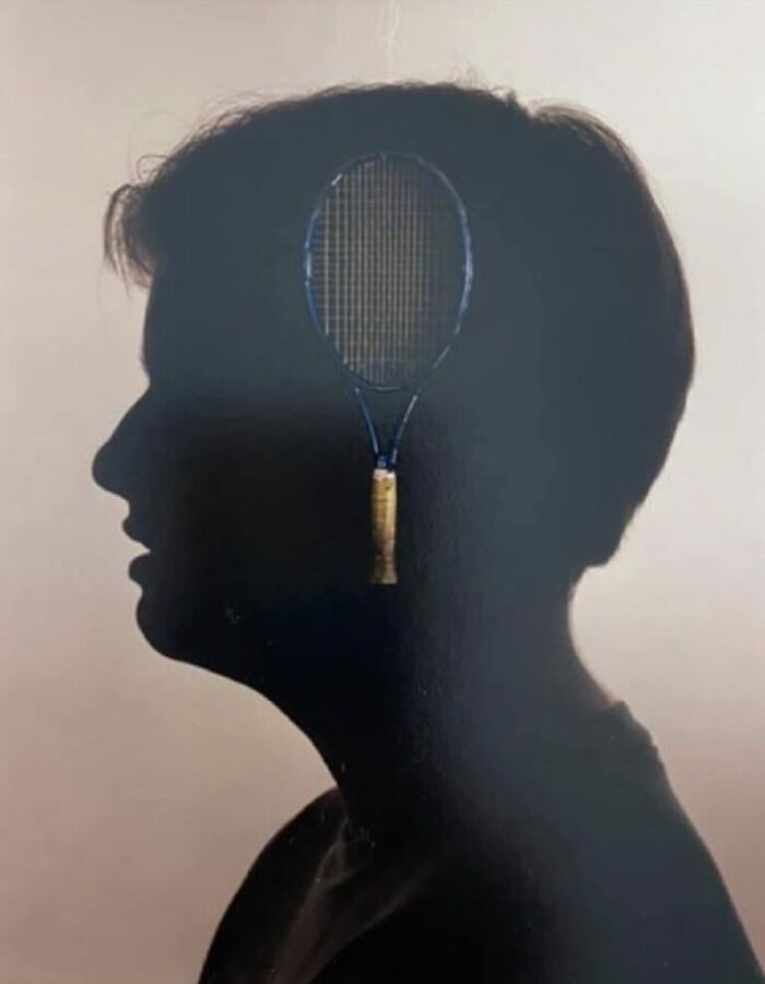Silhouette of a boy with a tennis racket perfectly aligned to look like part of his head in a funny school picture day fail.