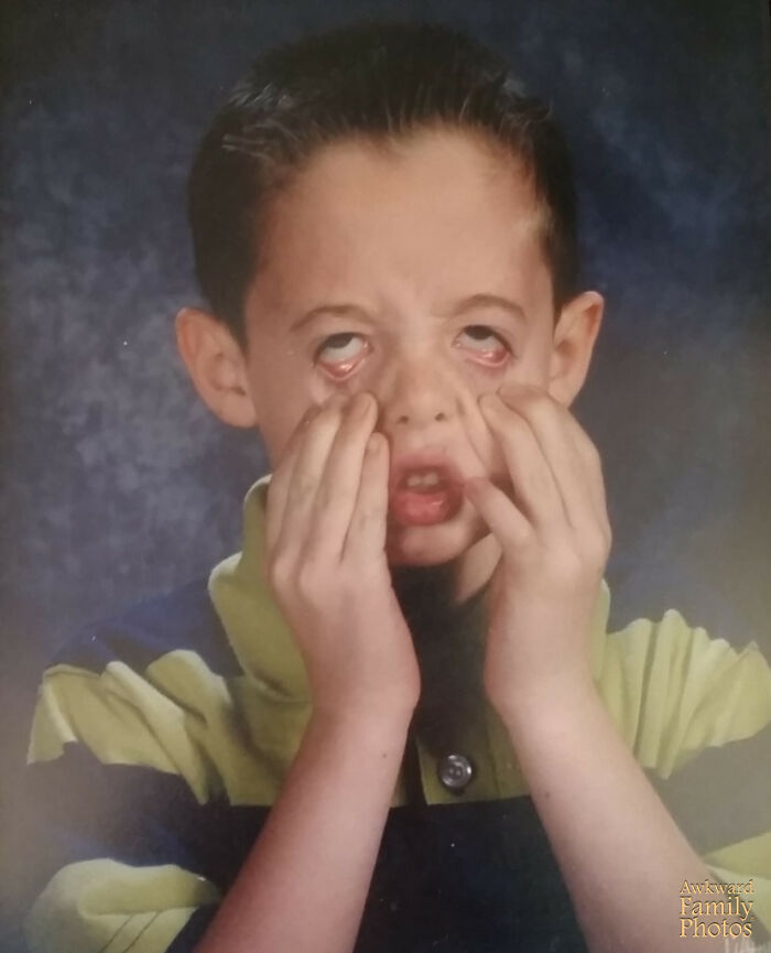 Boy making a funny face by pulling eyelids down during school picture day, a classic school picture day fail moment.