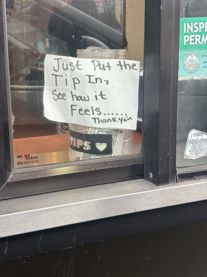 Handwritten sign on a tip jar at a window, encouraging tips with a humorous message causing double takes.