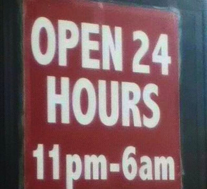 Red sign with white text humorously stating open 24 hours but listing hours as 11 pm to 6 am, funny sign example.